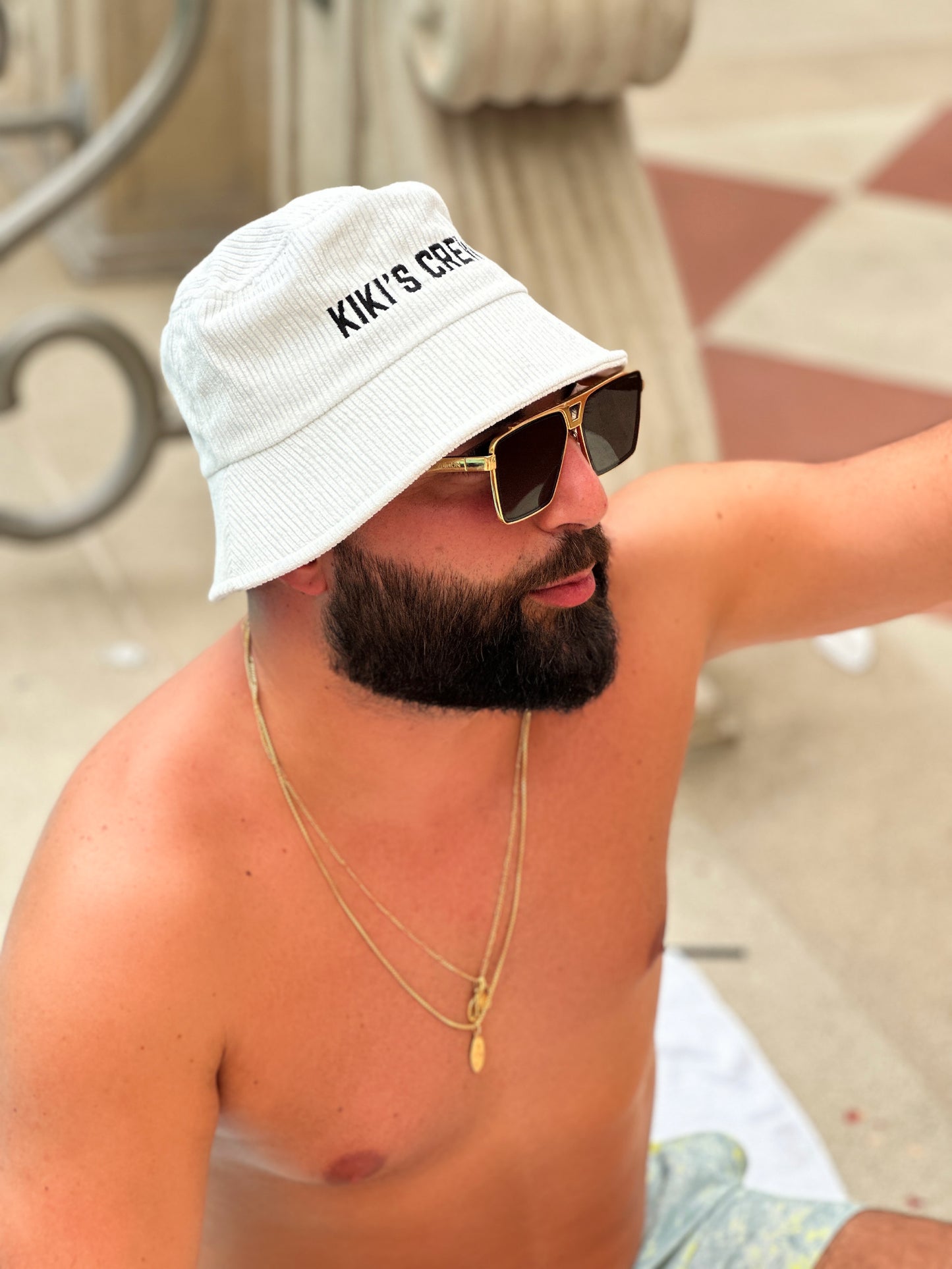 Model 3, male, wearing kiki's crew white corduroy bucket hat at the pool