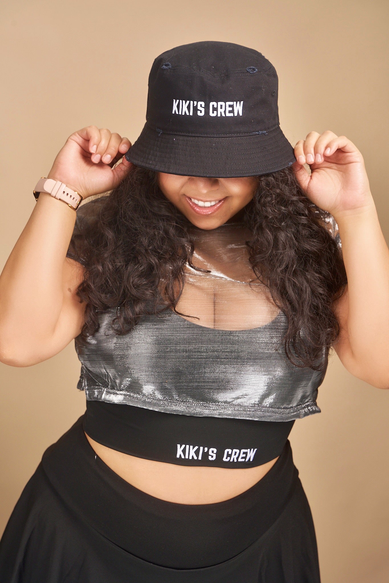 Female model wearing Kiki's crew black vintage bucket hat. this is a unisex product and accessory. she is also wearing kiki's crew metallic grey top with kiki's crew black sports bra size large and kiki's crew tennis skort size extra large