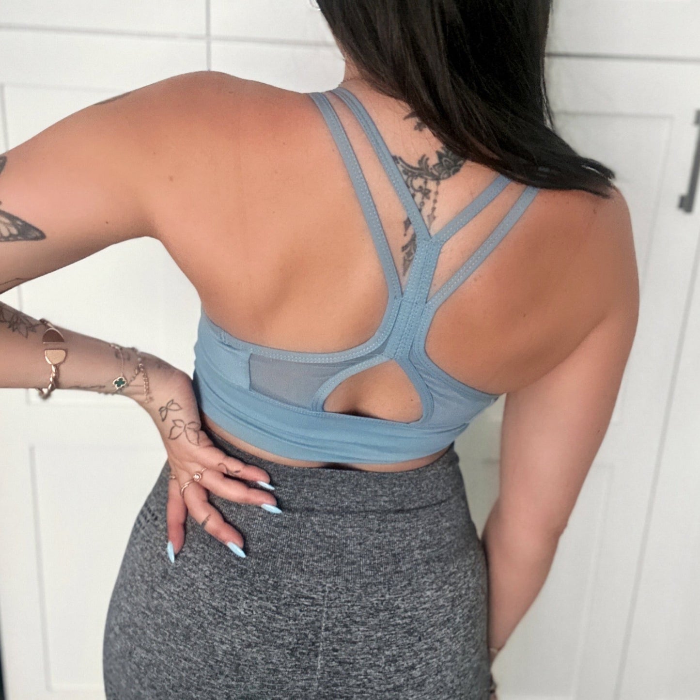 Model 1 showing the back of kiki's crew baby blue sports bra