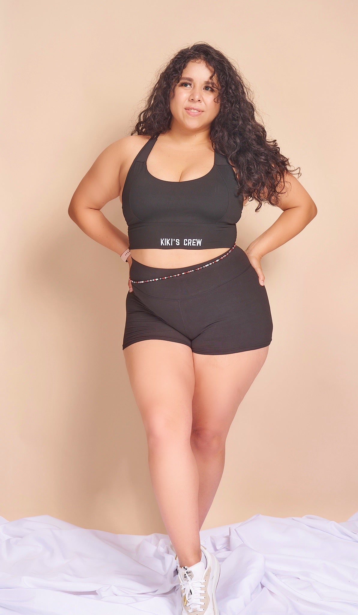 Model 2 wearing size large of kiki's crew black sports bra along with size large kiki's crew basic spandex shorts