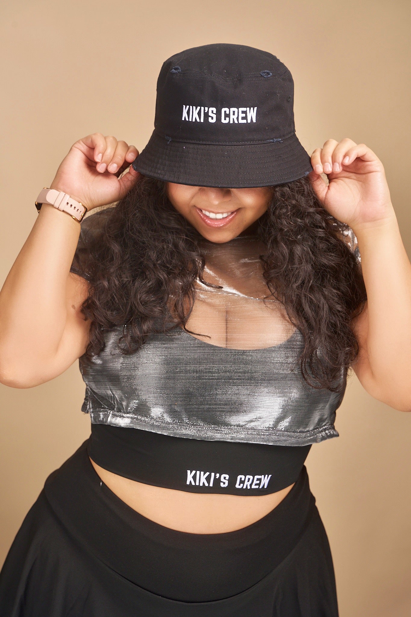 Female model wearing Kiki's crew black vintage bucket hat. this is a unisex product and accessory. she is also wearing kiki's crew metallic grey top with kiki's crew black sports bra size large and kiki's crew tennis skort size extra large 