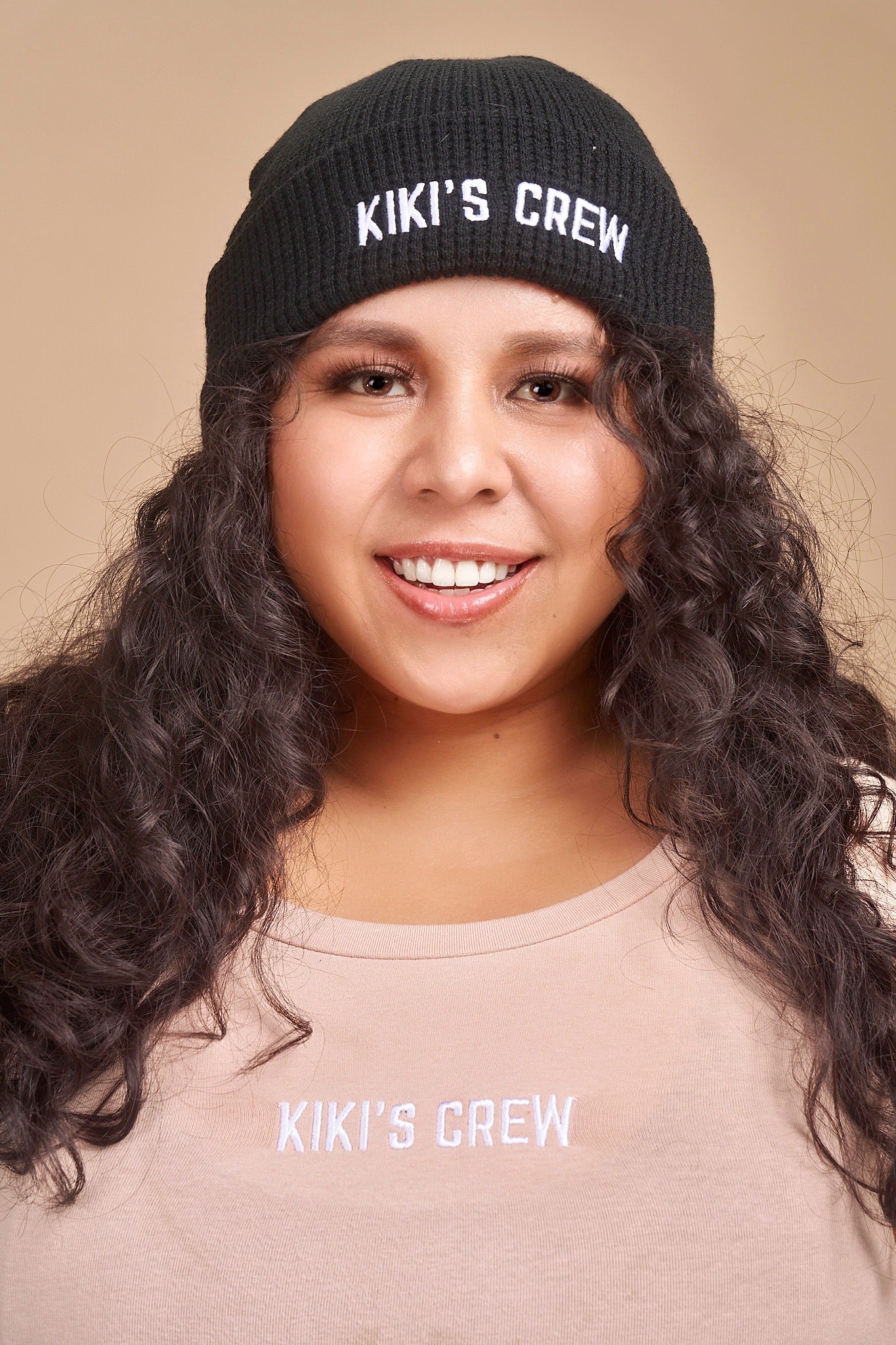 Model 2 wearing a black kiki's crew beanie. beanies are one size and unisex. she is also wearing a size large kiki's crew t-shirt 