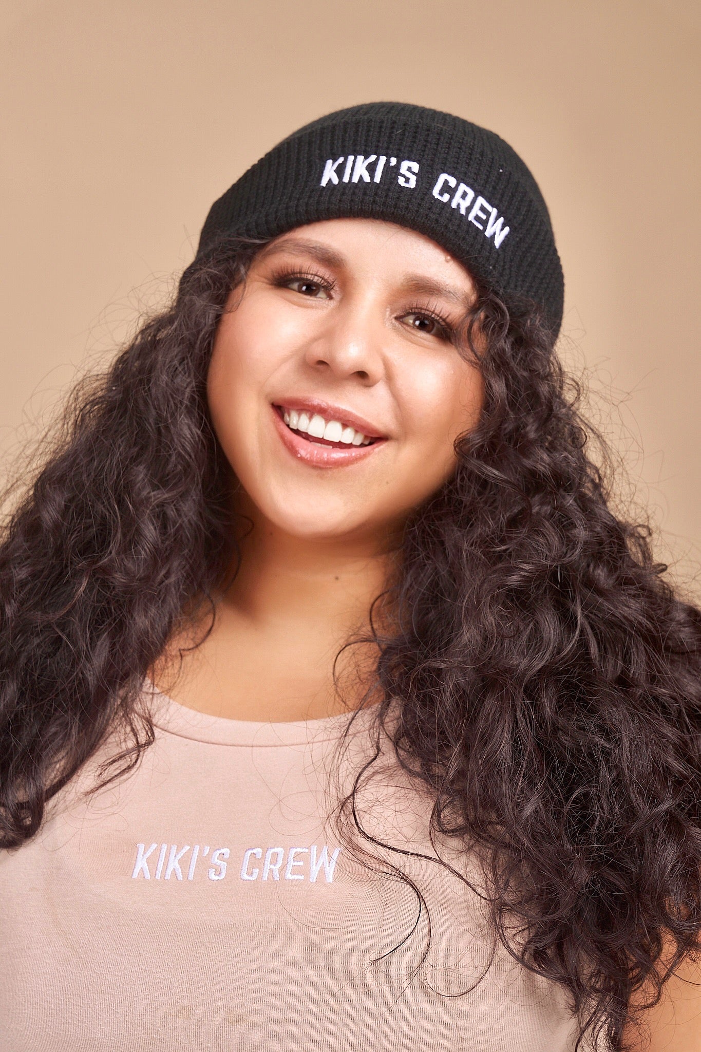 Model 2 wearing a black kiki's crew beanie. beanies are one size and unisex. she is also wearing a size large kiki's crew t-shirt 