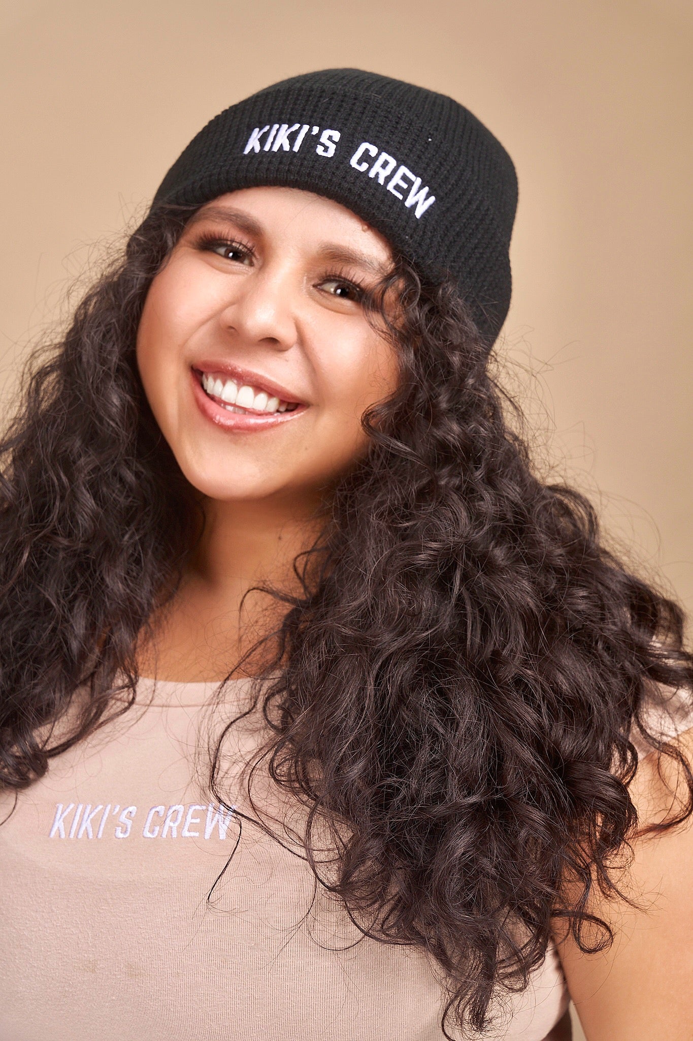 Model 2 wearing a black kiki's crew beanie. beanies are one size and unisex. she is also wearing a size large kiki's crew t-shirt 