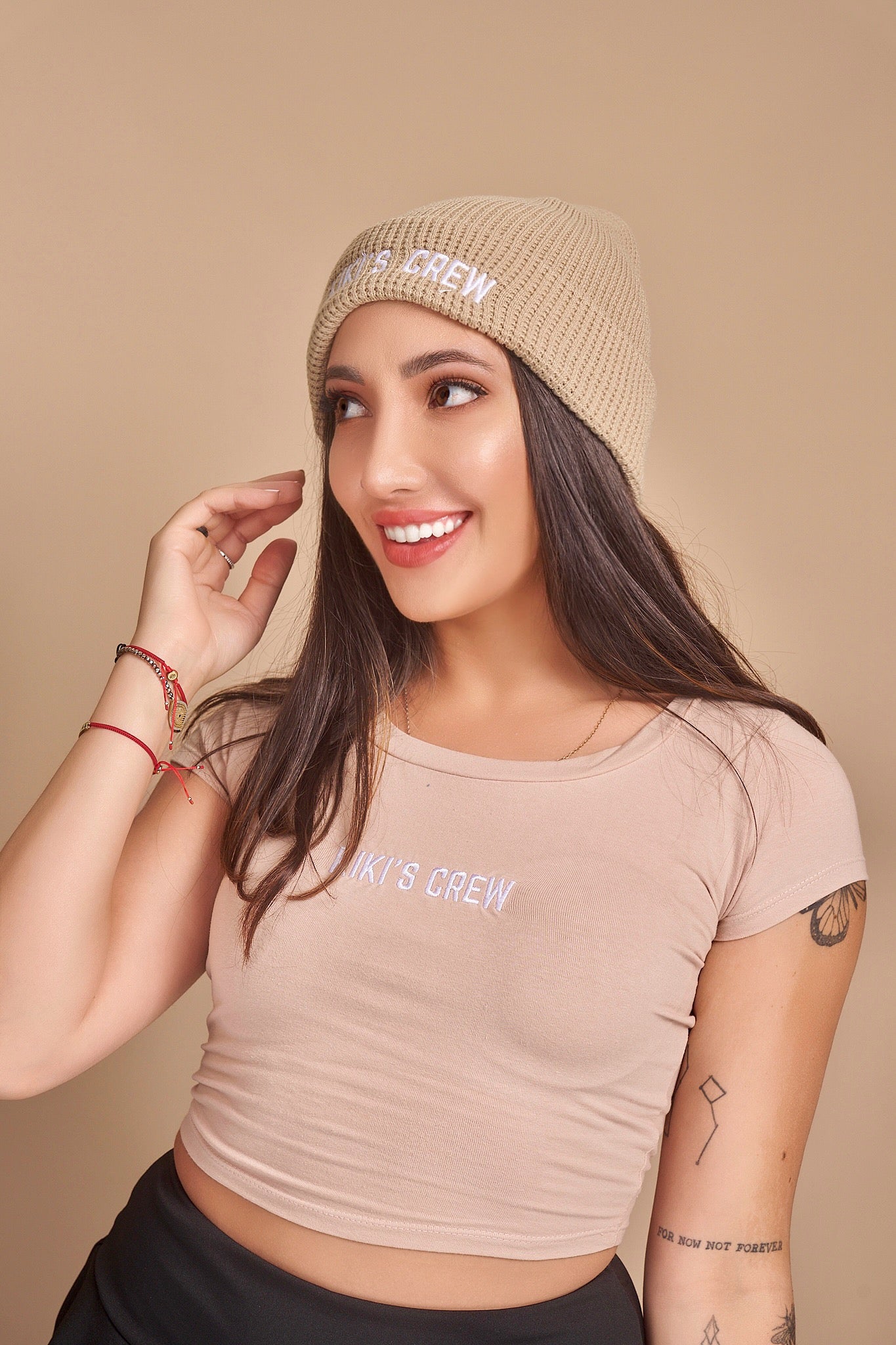 Model 1 is wearing a beige kiki's crew beanie. beanies are one size fits all and unisex. she is also wearing a size small kiki's crew t-shirt along with a kiki's crew size small tennis skort