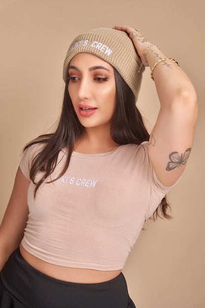 Model 1 is wearing a beige kiki's crew beanie. beanies are one size fits all and unisex. she is also wearing a size small kiki's crew t-shirt along with a kiki's crew size small tennis skort