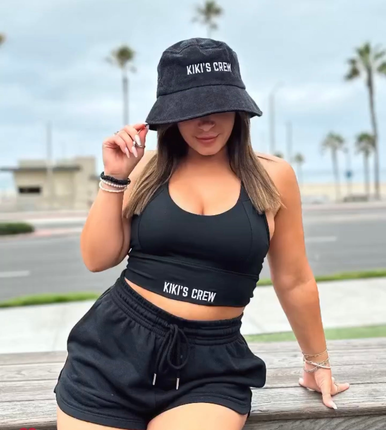 Female customer wearing kiki's crew black sports bra medium along with kiki's crew basic scrunch shorts and kiki's crew black corduroy bucket hat 