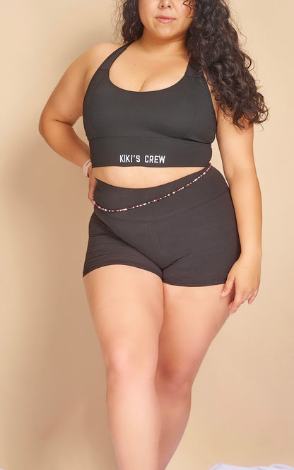 Model 2 wearing size large of kiki's crew black sports bra along with size large kiki's crew basic spandex shorts 